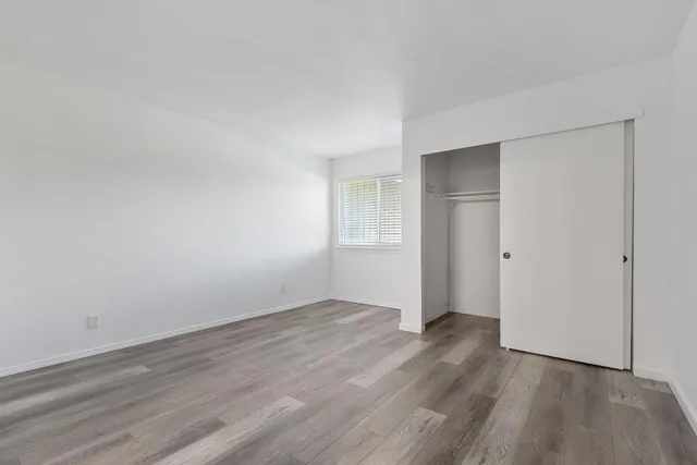 a view of an empty room with wooden floor and closet