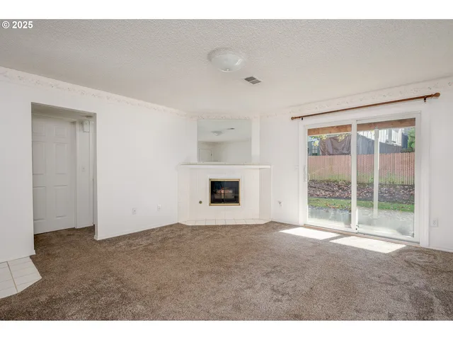 a view of an empty room with a fireplace and a window