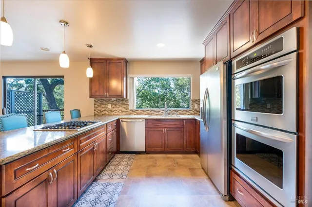 a large kitchen with stainless steel appliances granite countertop a stove a sink and a microwave