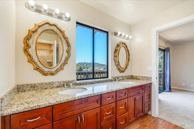 a bathroom with a granite countertop double vanity sink and a mirror