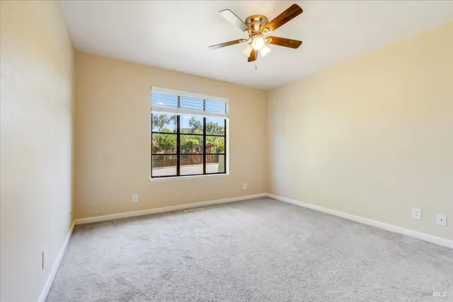 an empty room with windows and chandelier fan