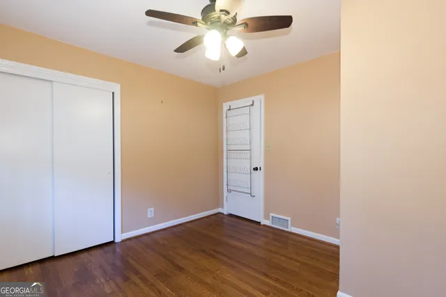 a view of an empty room with window a ceiling fan and wooden floor