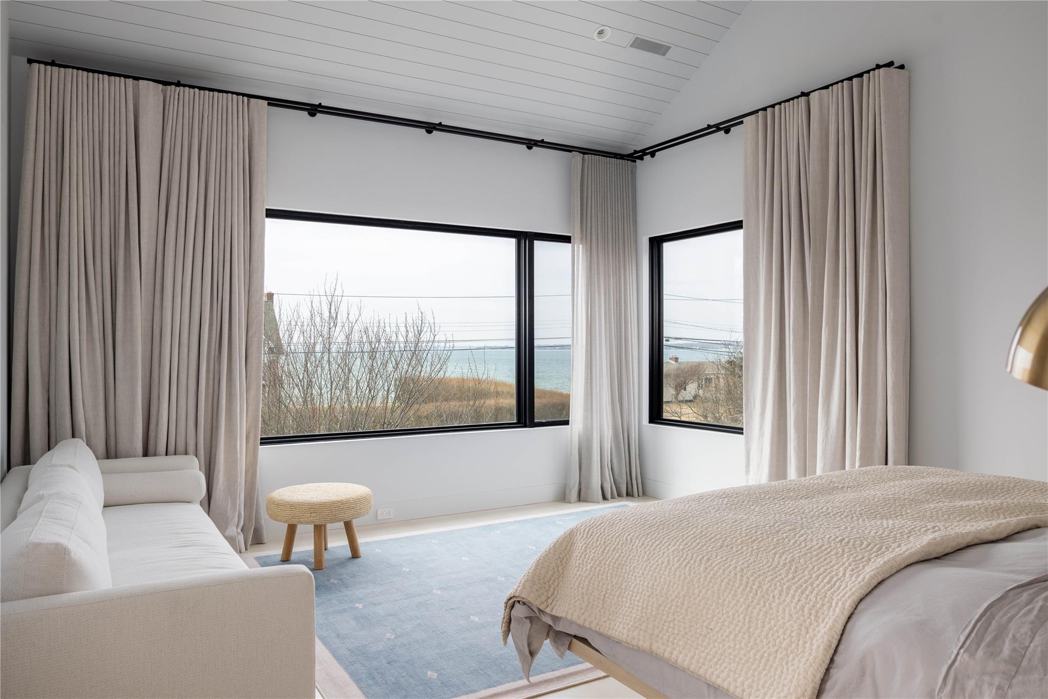 61 Peconic Avenue Shelter Island Heights, NY 11964 - Photo 9 of 27 a bedroom with a large bed and a large window