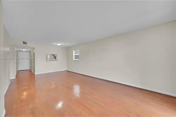 a view of an empty room with wooden floor and a window