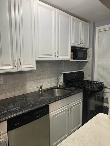 a kitchen with granite countertop white cabinets and black appliances