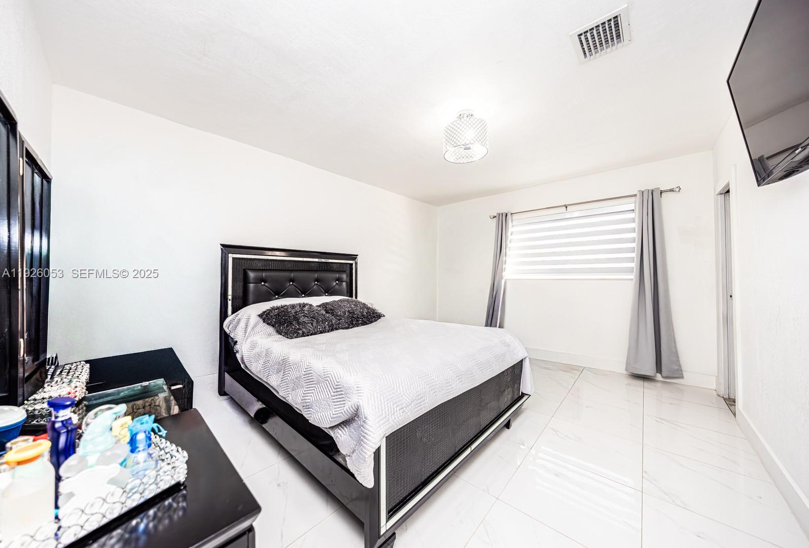 9365 Southwest 44th Street Miami, FL 33165 - Photo 18 of 24 a bedroom with a bed window and a flat screen tv