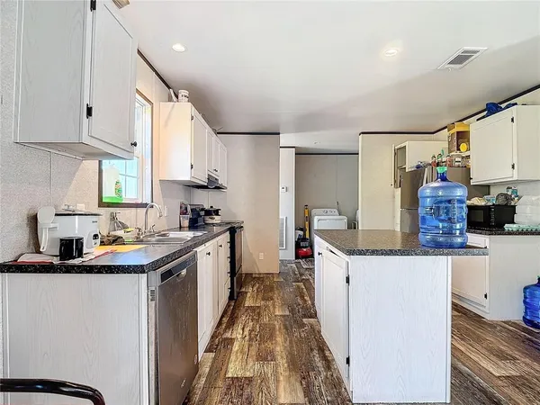 a kitchen with a sink appliances and wooden floor