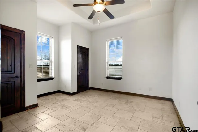 a view of an empty room with window and chandelier fan