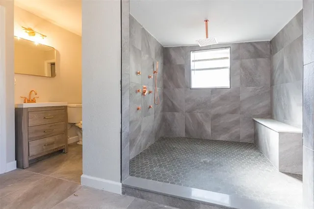 a bathroom with a granite countertop sink a toilet a mirror and shower