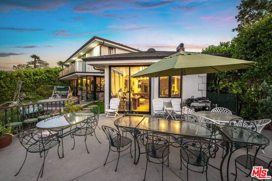 10061 Valley Spring Lane Toluca Lake, CA 91602 - Photo 10 of 37 a patio with a table and chairs under an umbrella