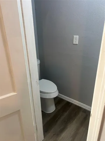 a white toilet sitting next to a wooden vanity