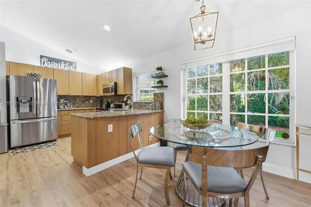 a kitchen with stainless steel appliances granite countertop a stove a refrigerator a kitchen island a table and chairs