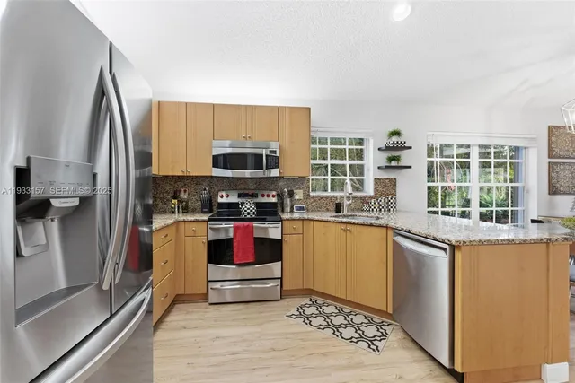 a kitchen with stainless steel appliances granite countertop a refrigerator sink and stove