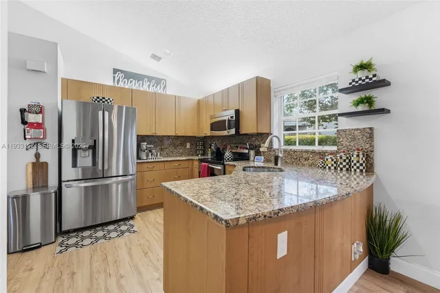 a kitchen with stainless steel appliances granite countertop a refrigerator a stove and a sink