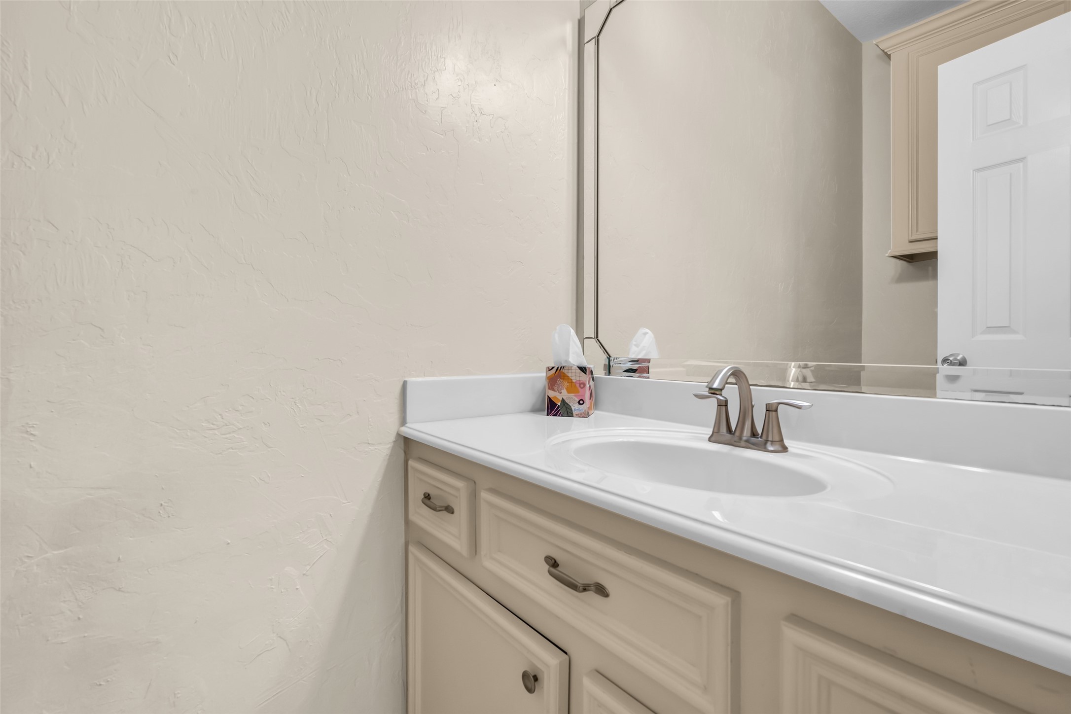 1898 Longmire Road, Unit 5 Conroe, TX 77304 - Photo 28 of 48 This photo showcases a clean, modern bathroom with a white countertop, built-in sink, and elegant faucet. The light-colored cabinetry and large mirror enhance the sense of space and brightness.