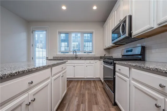 a kitchen with granite countertop cabinets stainless steel appliances a sink and window