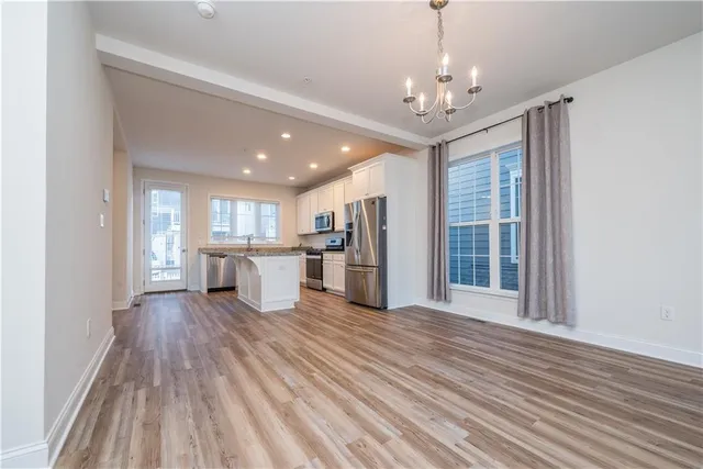a view of a hallway with wooden floor and a kitchen
