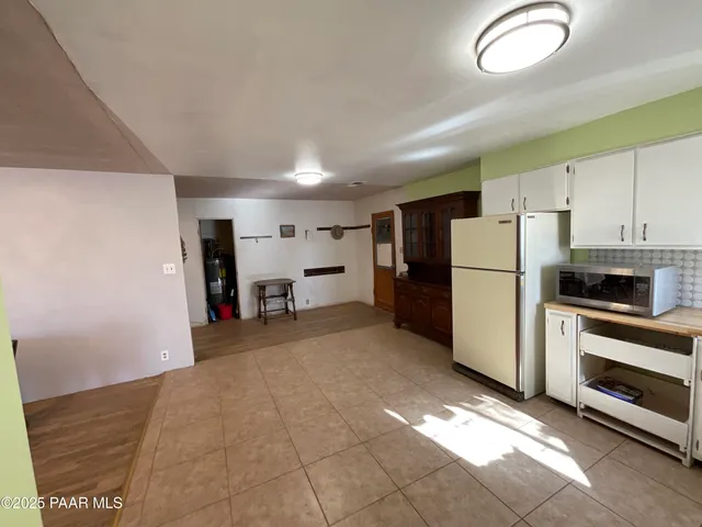 a view of a kitchen with refrigerator and white cabinets