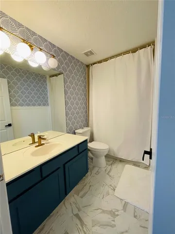 a bathroom with a granite countertop sink mirror vanity and toilet