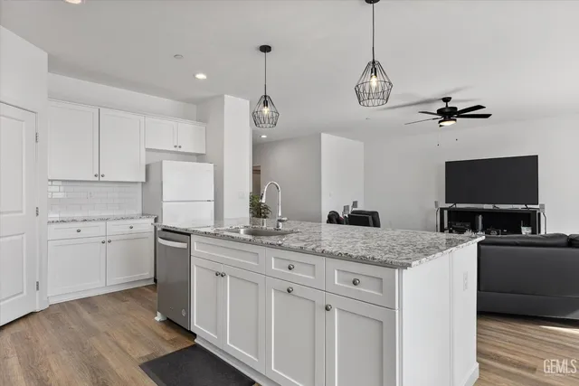 a kitchen with stainless steel appliances granite countertop a sink a stove a refrigerator and island with wooden floor