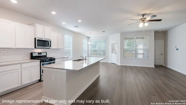 a large kitchen with stainless steel appliances granite countertop a sink dishwasher a stove and a microwave oven with white cabinets