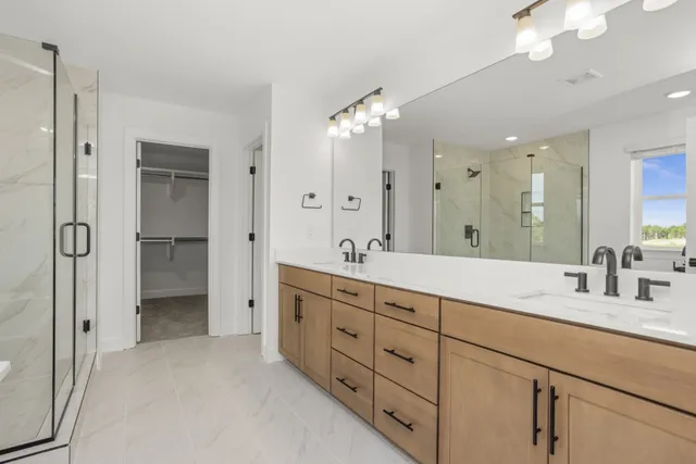 a bathroom with double vanity sinks a vanity a lamp and a shower