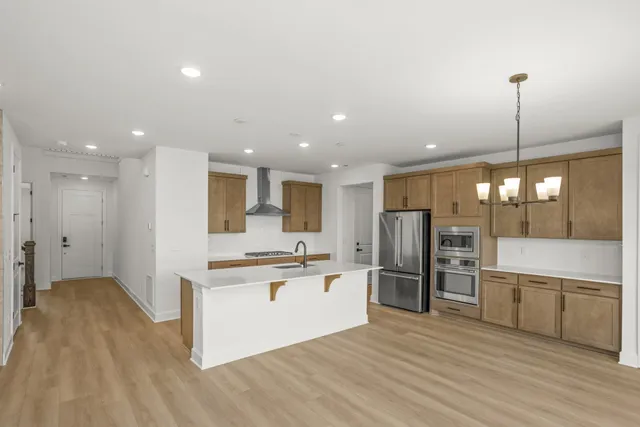 a large kitchen with stainless steel appliances kitchen island a large counter top and wooden floors