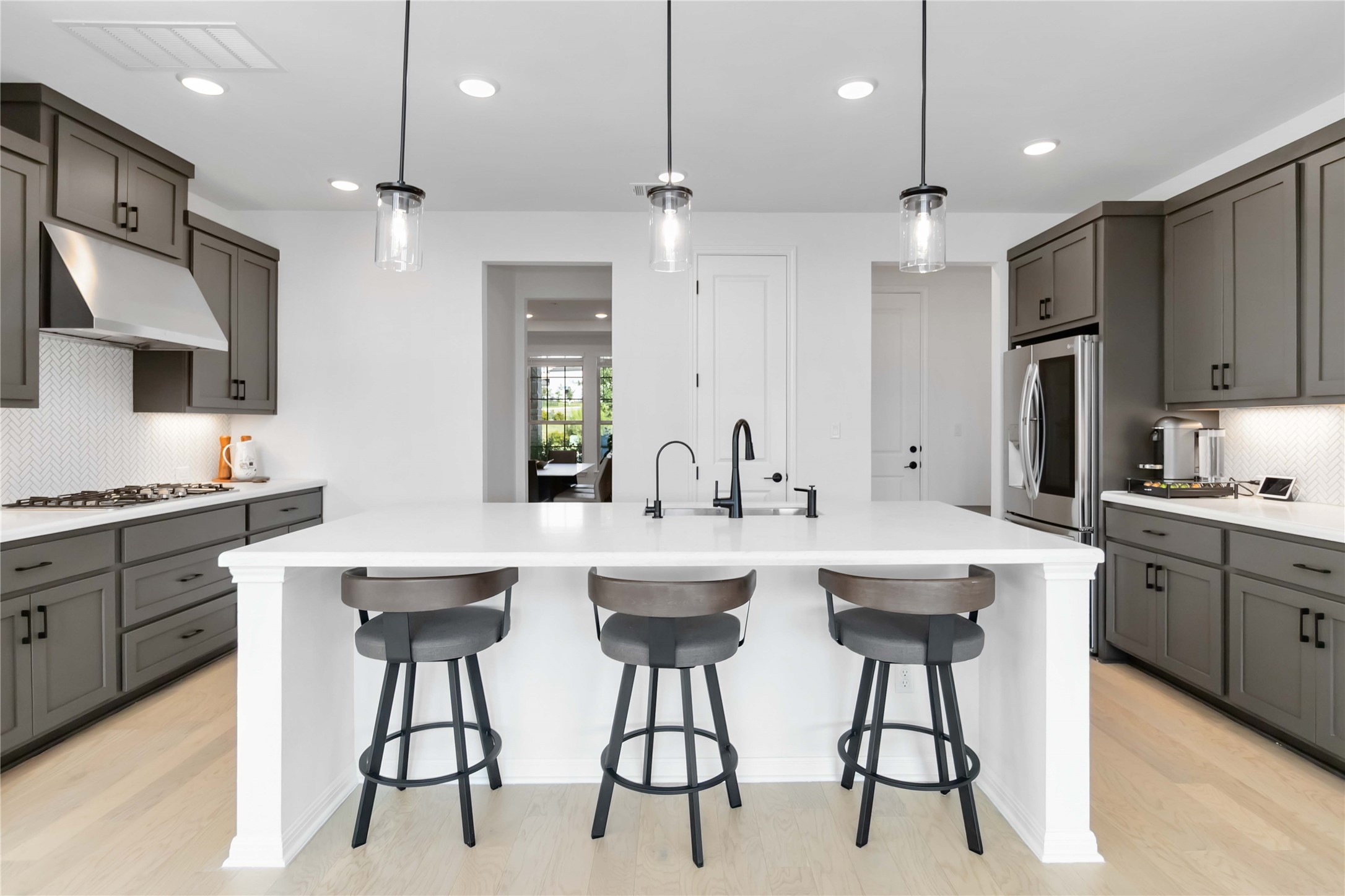 4705 Modena Bay Bend Leander, TX 78641 - Photo 11 of 40 Kitchen featuring backsplash, quartz countertops, center island with MotionSense faucet and black matte fixtures, recessed lighting, under cabinet range hood