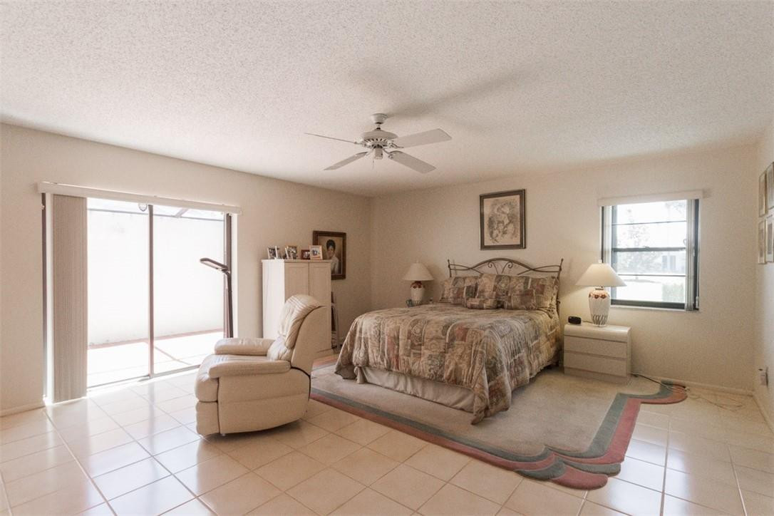 9096 Southwest 20th Street, Unit F Boca Raton, FL 33428 - Photo 9 of 35 a spacious bedroom with a bed and a chandelier