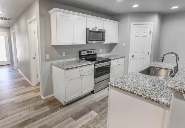 a kitchen with granite countertop a sink and a stove top oven