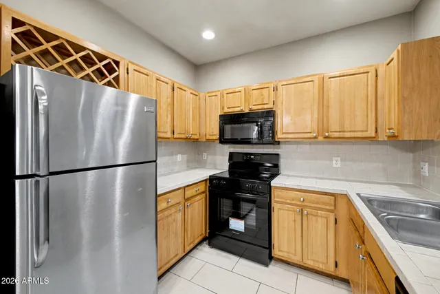 a kitchen with stainless steel appliances granite countertop a refrigerator a sink a stove top oven and cabinets