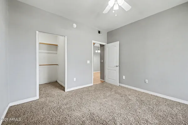 an empty room with closet and a chandelier fan