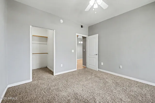 an empty room with closet and a chandelier fan