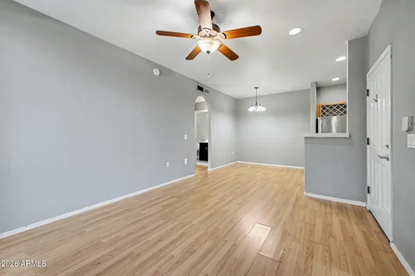 a view of empty room with wooden floor and fan