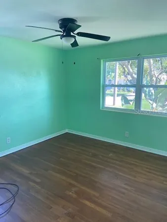 a view of an empty room with a window and wooden floor