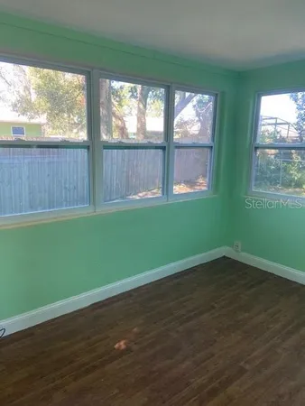 an empty room with wooden floor and a yard