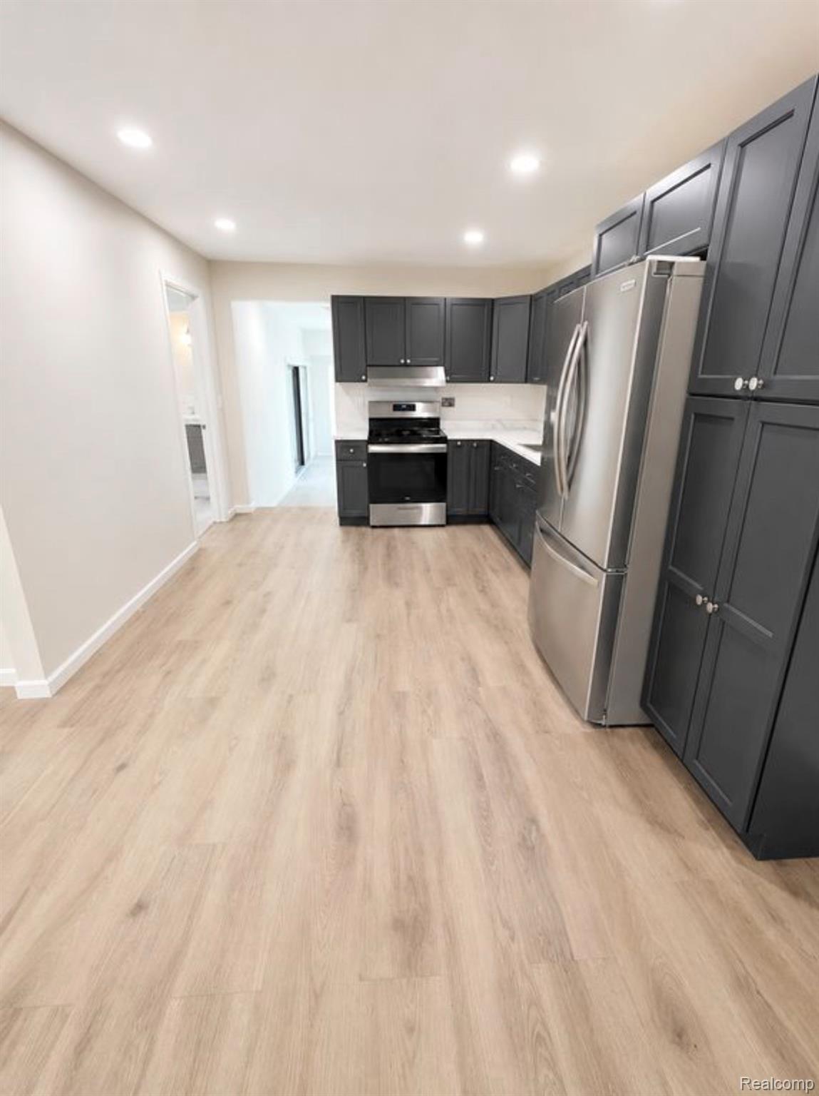 3428 Hazelton Avenue Rochester, MI 48307 - Photo 4 of 5 Modern kitchen featuring dark cabinetry, stainless steel appliances, light wood-finish flooring, recessed lighting, and white countertops with a matching backsplash