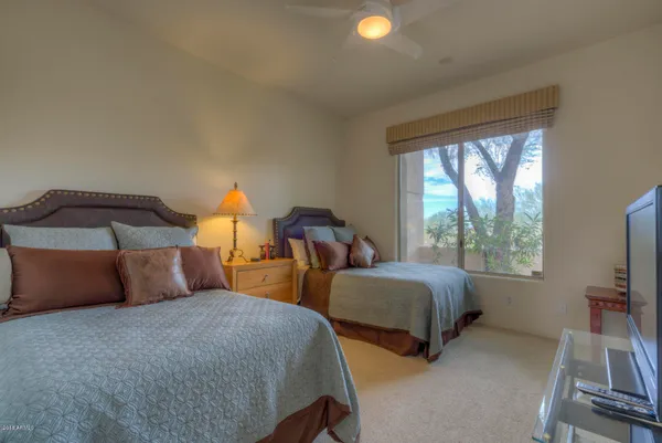 a bedroom with two beds and a flat tv screen on dresser