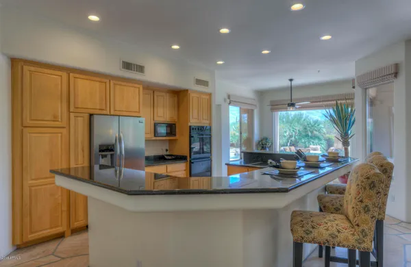 a kitchen with stainless steel appliances granite countertop a refrigerator a stove and a sink with wooden floor
