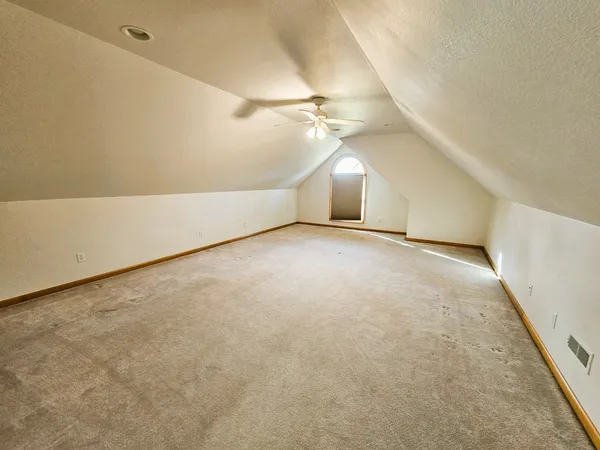 an empty room with a ceiling fan and carpet