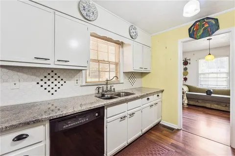 a kitchen with granite countertop a sink a window and cabinets