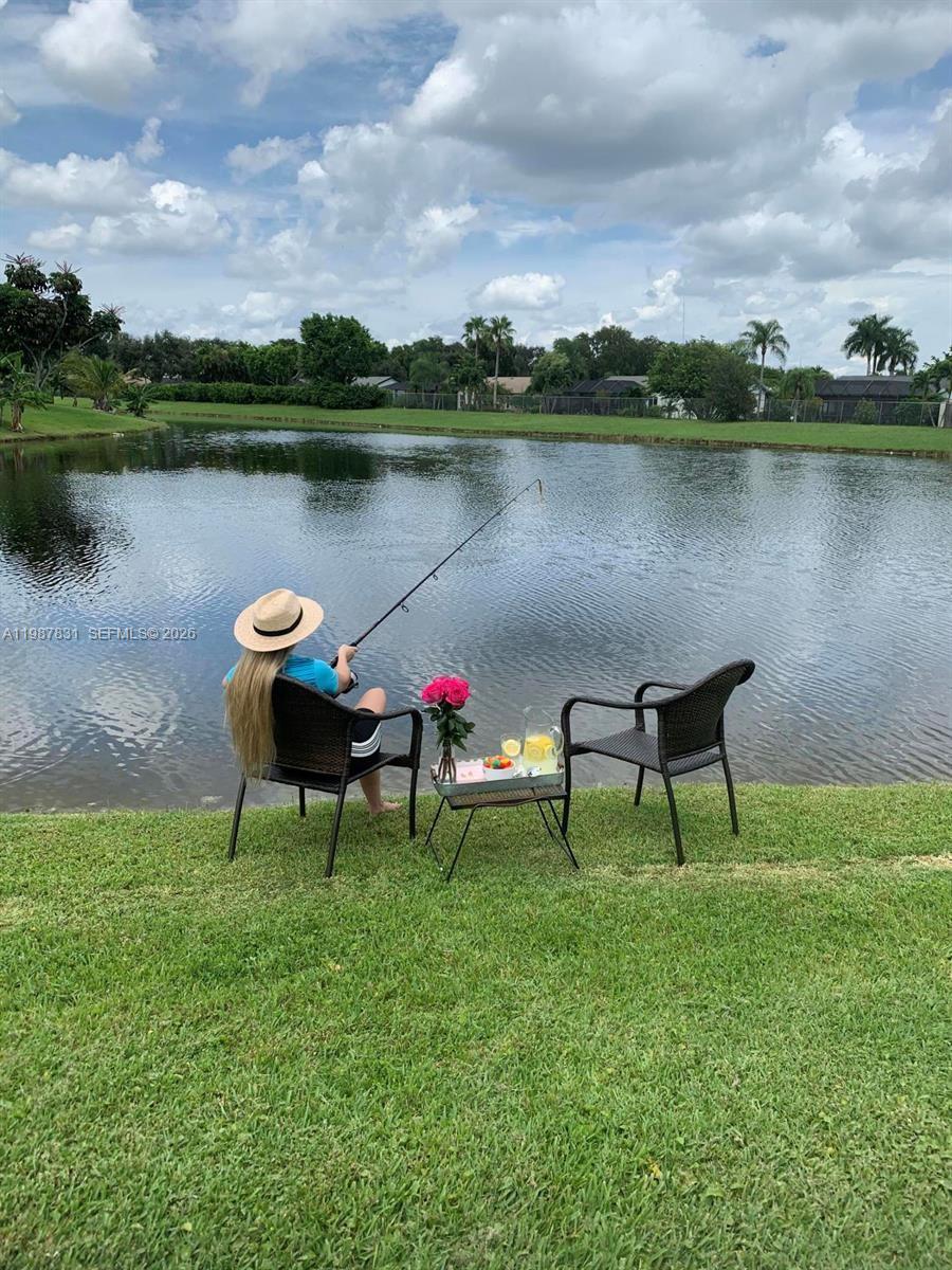 18551 Woodstream Drive Boca Raton, FL 33498 - Photo 16 of 27 an outdoor sitting area with couch and a lake view