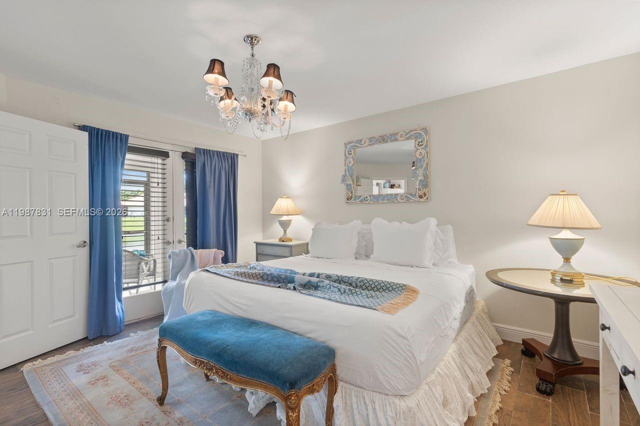 18551 Woodstream Drive Boca Raton, FL 33498 - Photo 18 of 27 a bedroom with a bed and a chandelier