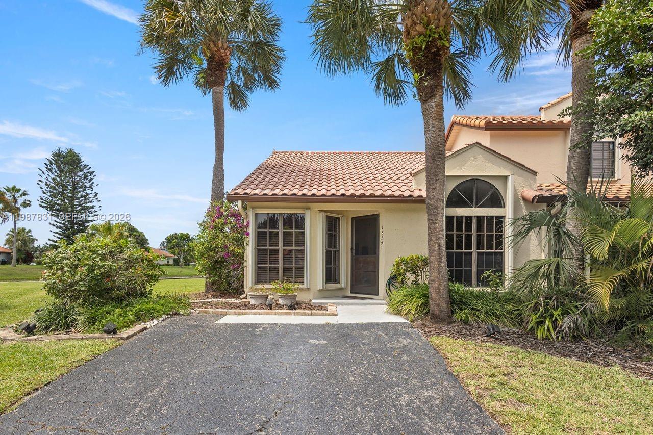 18551 Woodstream Drive Boca Raton, FL 33498 - Photo 2 of 27 a view of a white house with a large window and palm trees