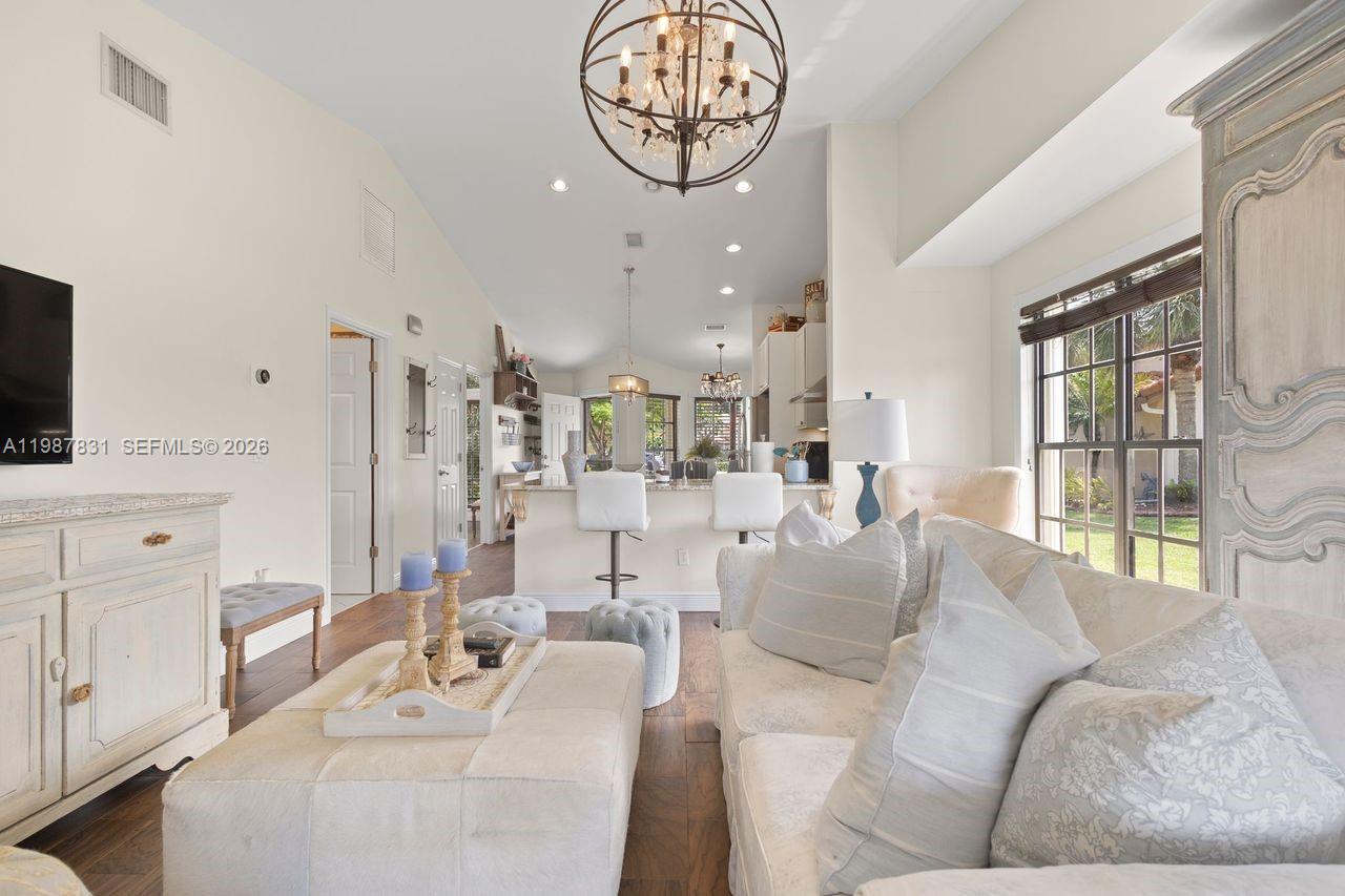 18551 Woodstream Drive Boca Raton, FL 33498 - Photo 8 of 27 a living room with furniture a chandelier and a flat screen tv