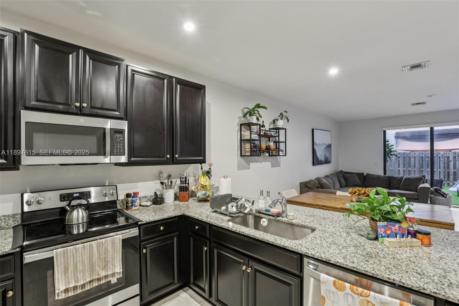 23291 Southwest 110th Court Homestead, FL 33032 - Photo 12 of 41 a kitchen with stainless steel appliances granite countertop a sink stove and microwave