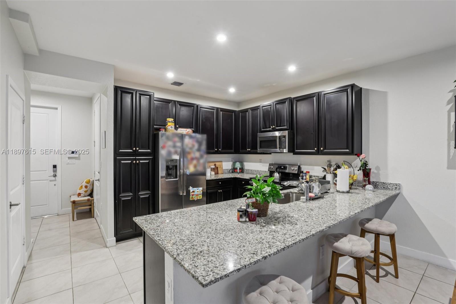 23291 Southwest 110th Court Homestead, FL 33032 - Photo 13 of 41 a kitchen with kitchen island granite countertop wooden cabinets a refrigerator and a sink
