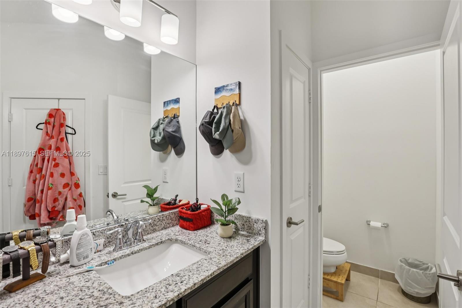 23291 Southwest 110th Court Homestead, FL 33032 - Photo 22 of 41 a bathroom with a granite countertop sink a toilet and curtain