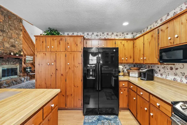 a kitchen with stainless steel appliances granite countertop a refrigerator a stove and a sink with wooden floors