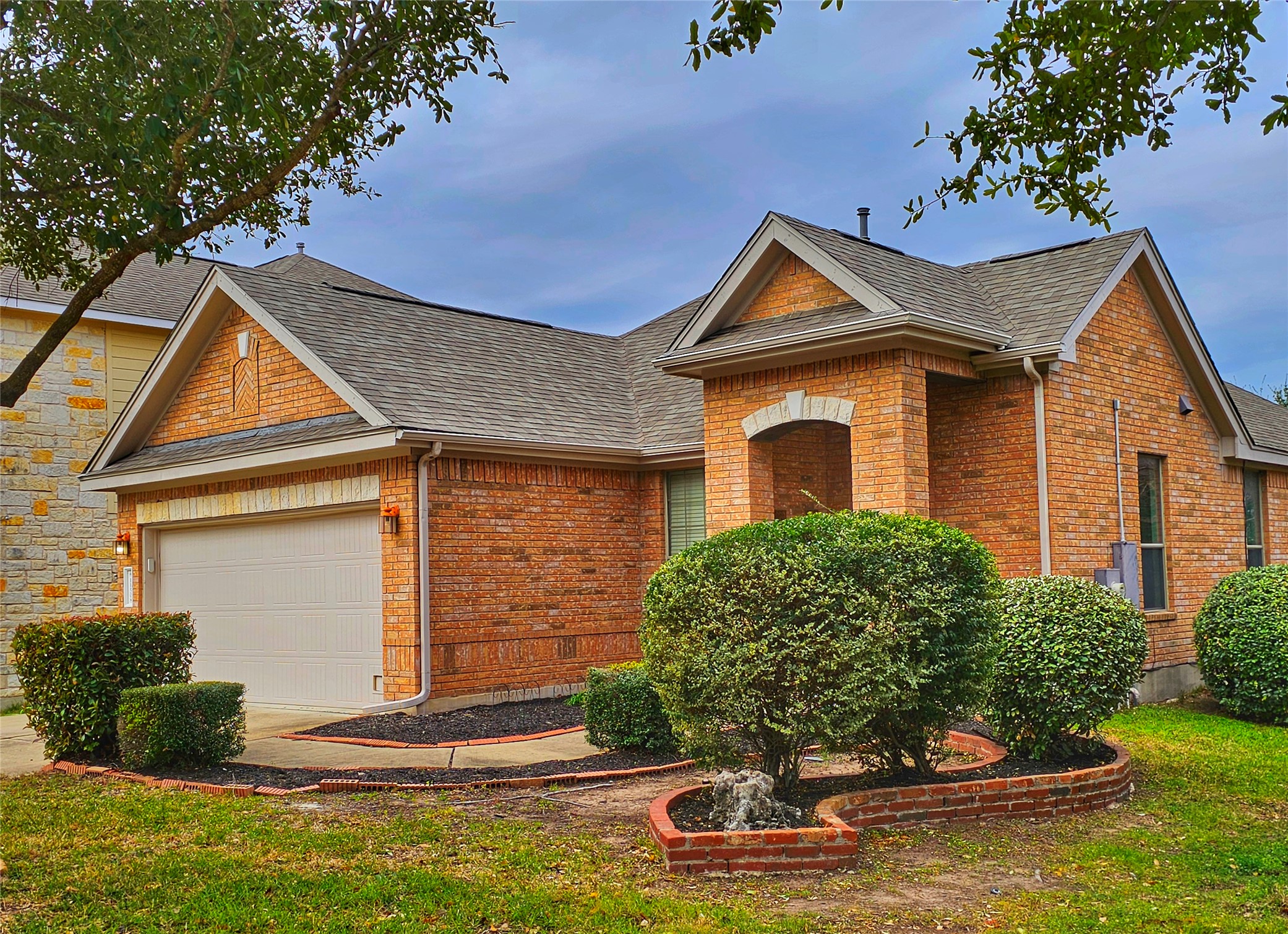 View of front of property featuring brick siding, a shingled roof, a garage, and a front yard